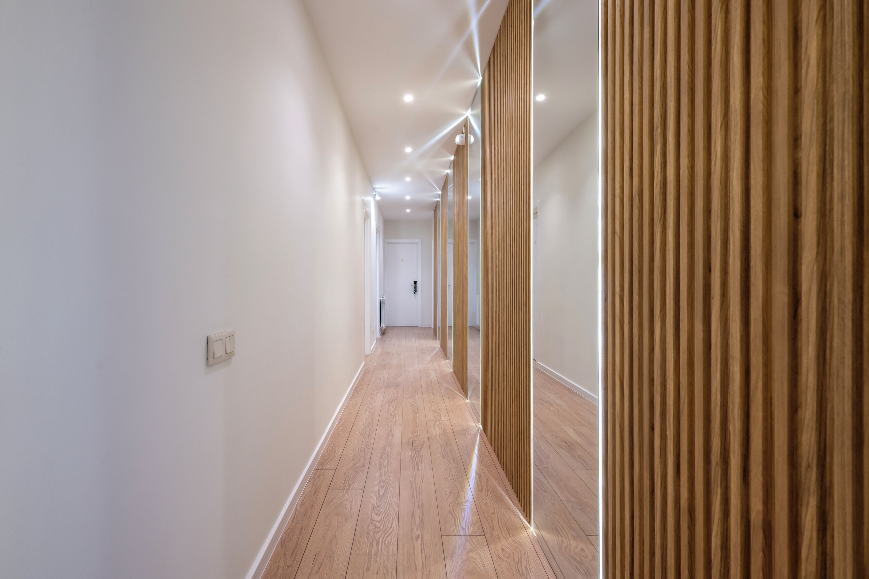 Un pasillo moderno con paneles de madera en una pared y suelo de color claro.