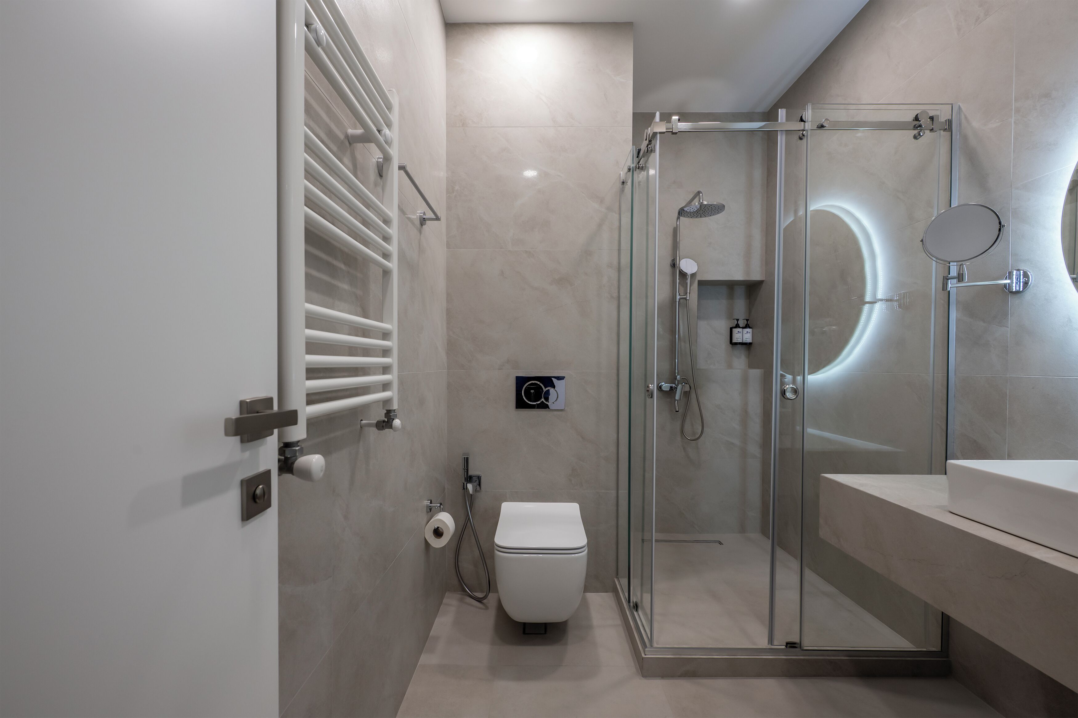 Ein modernes Badezimmer mit einer Duschkabine, einer Toilette und einem Waschbecken mit Spiegel.