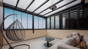 Un balcon moderne agrémenté d’un fauteuil suspendu, d’une petite table et d’un canapé avec des coussins.