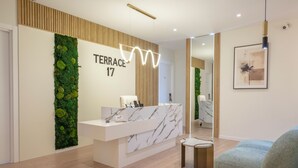 Un espace d’accueil moderne avec un comptoir en marbre, un jardin vertical verdoyant et une œuvre d’art encadrée au mur.