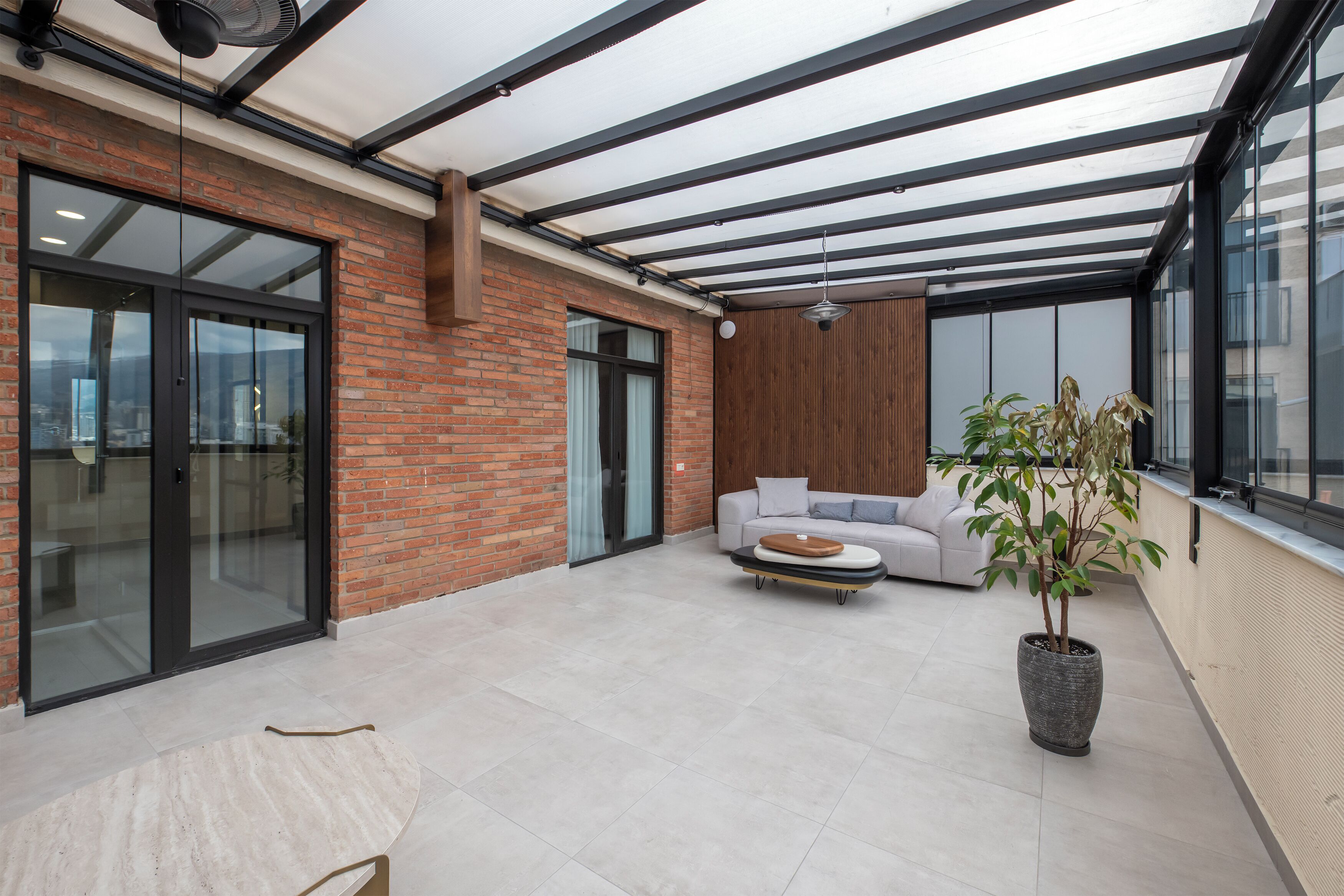 A modern indoor space with a glass door entrance, a sofa, a coffee table, and a potted plant.