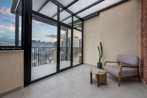 A balcony with large glass doors, a chair, a small table, and a potted plant. - Terrace 17 By Doors (Tbilisi)