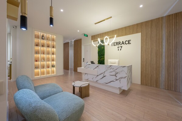 A modern reception area with a marble counter, a seating area with a blue sofa, and a wall display of bottles. - Terrace 17 By Doors (Tbilisi)