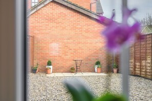A brick building with a gravel patio, a metal table, and potted plants. - Host and Stay - The Rowton (Norwich)