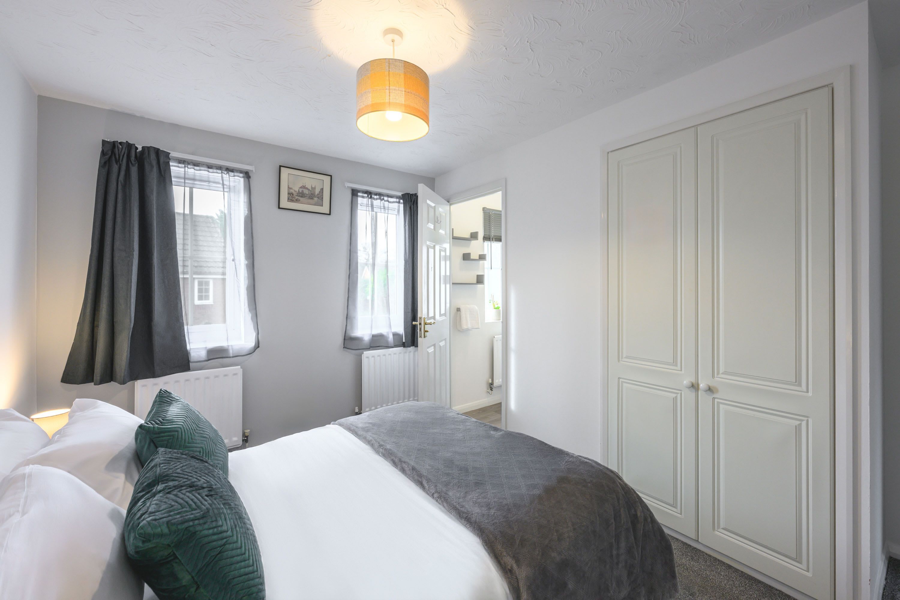A bedroom with a bed, a wardrobe, and a window with curtains.