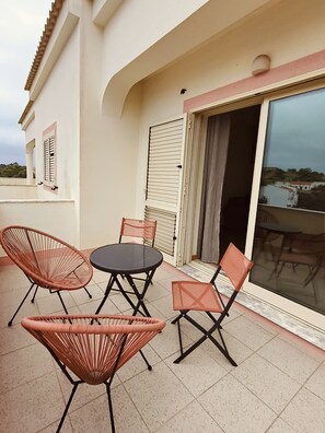 Un balcon avec une table et quatre chaises, une porte-fenêtre coulissante et une vue sur le paysage.