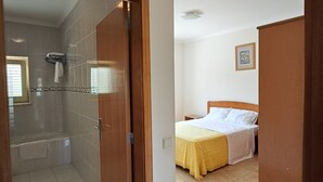 Ein Hotelzimmer mit Bad, einem Bett mit gelber Bettdecke und einem Holzschrank.