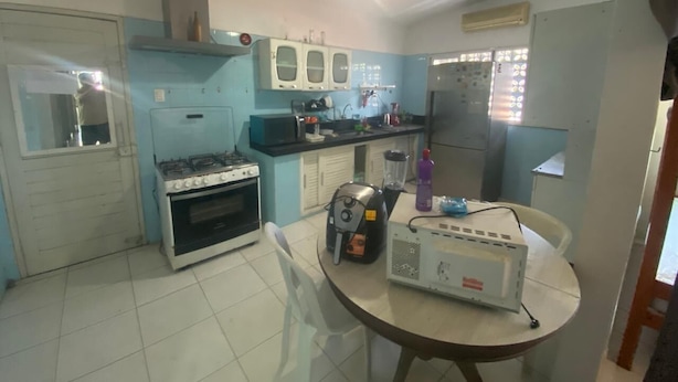 A compact kitchen with a gas stove, oven, and a small refrigerator. - Hostel Suites (Recife)