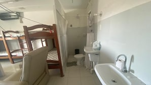 A compact bathroom with a wooden chair, a sink, and a toilet. - Hostel Suites (Recife)