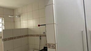 A bathroom with white tiles, a shower, a toilet, and a sink. - Hostel Suites (Recife)