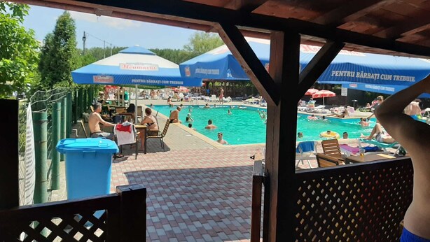Ett poolområde med parasoller och folk som badar.