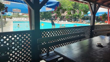 Un área de piscina techada con sillones reclinables y una mesa.