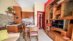 Un espacio habitable compacto con kitchenette, comedor y zona de estar.
