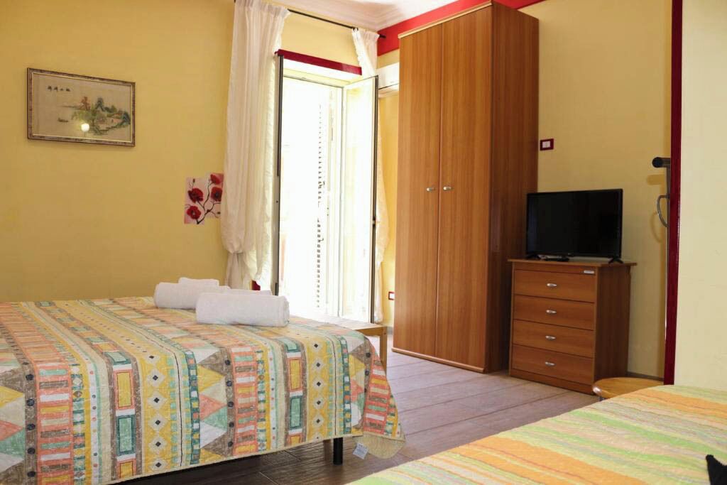 Una camera da letto con un letto, una televisione su una cassettiera in legno e un armadio.