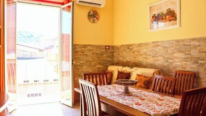 Un comedor con una mesa preparada para cuatro personas, un sofá y un reloj de pared.