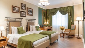 A hotel room with two beds, a desk, a chair, a lamp, a mirror, and framed pictures on the wall. - Hayasa Hotel Old Yerevan (Yerevan)
