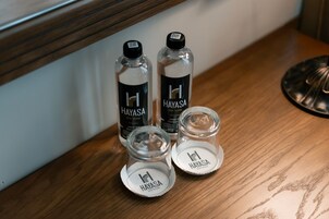 Twee flessen en twee glazen bakken met de merknaam 'Hayasa' op een houten ondergrond.