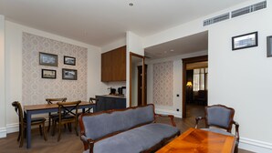 A dining area with a wooden table, chairs, a sofa, and a kitchen in the background. - Hayasa Hotel Old Yerevan (Yerevan)