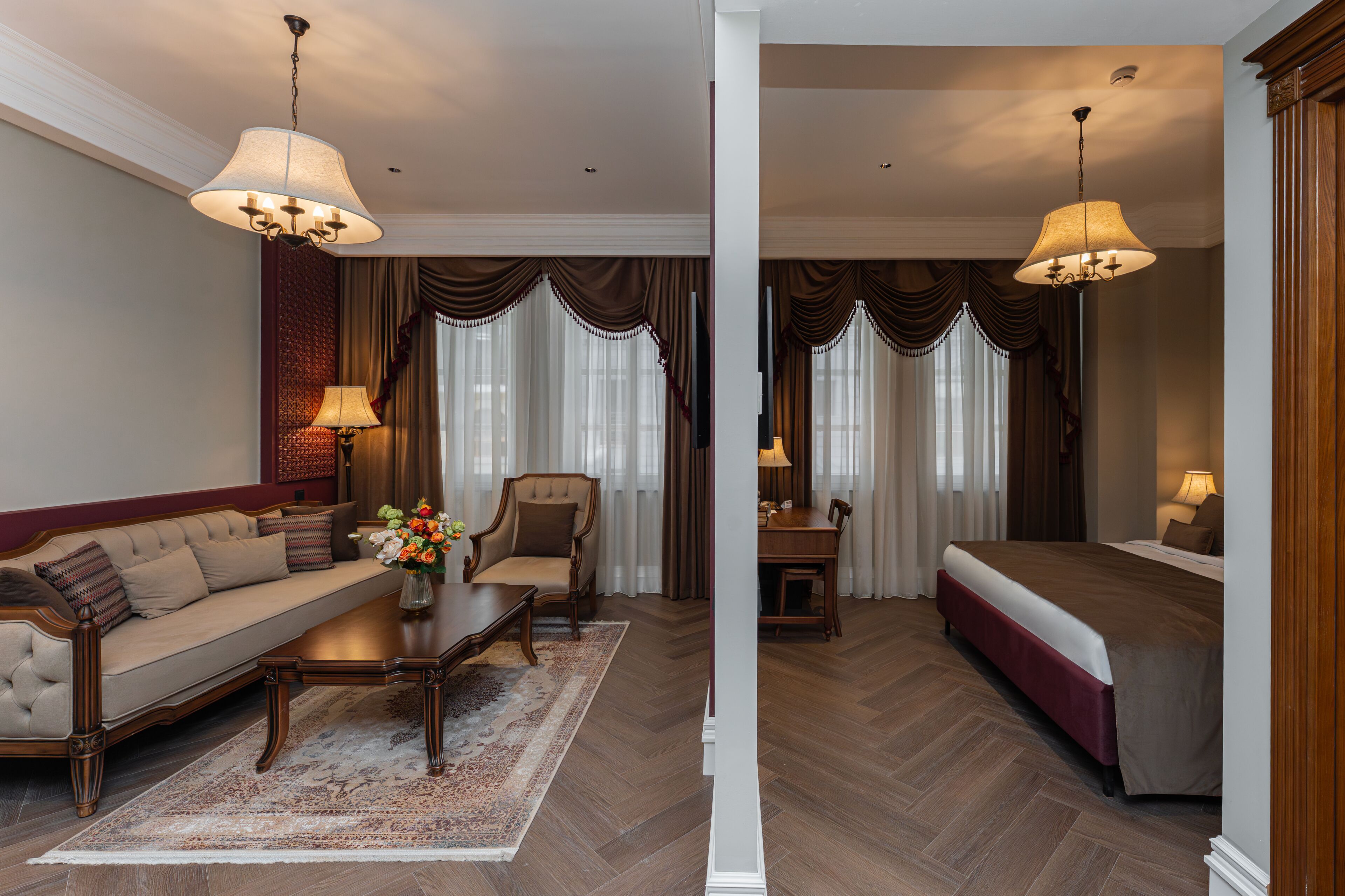A hotel room with a sofa, a dining table, a bed, and a chandelier.