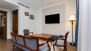 A room with a wooden dining table, two chairs, a television on the wall, and a floor lamp. - Hayasa Hotel Old Yerevan (Yerevan)