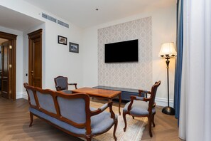 Une pièce comprenant une table à manger en bois, deux chaises, un téléviseur fixé au mur et un lampadaire.