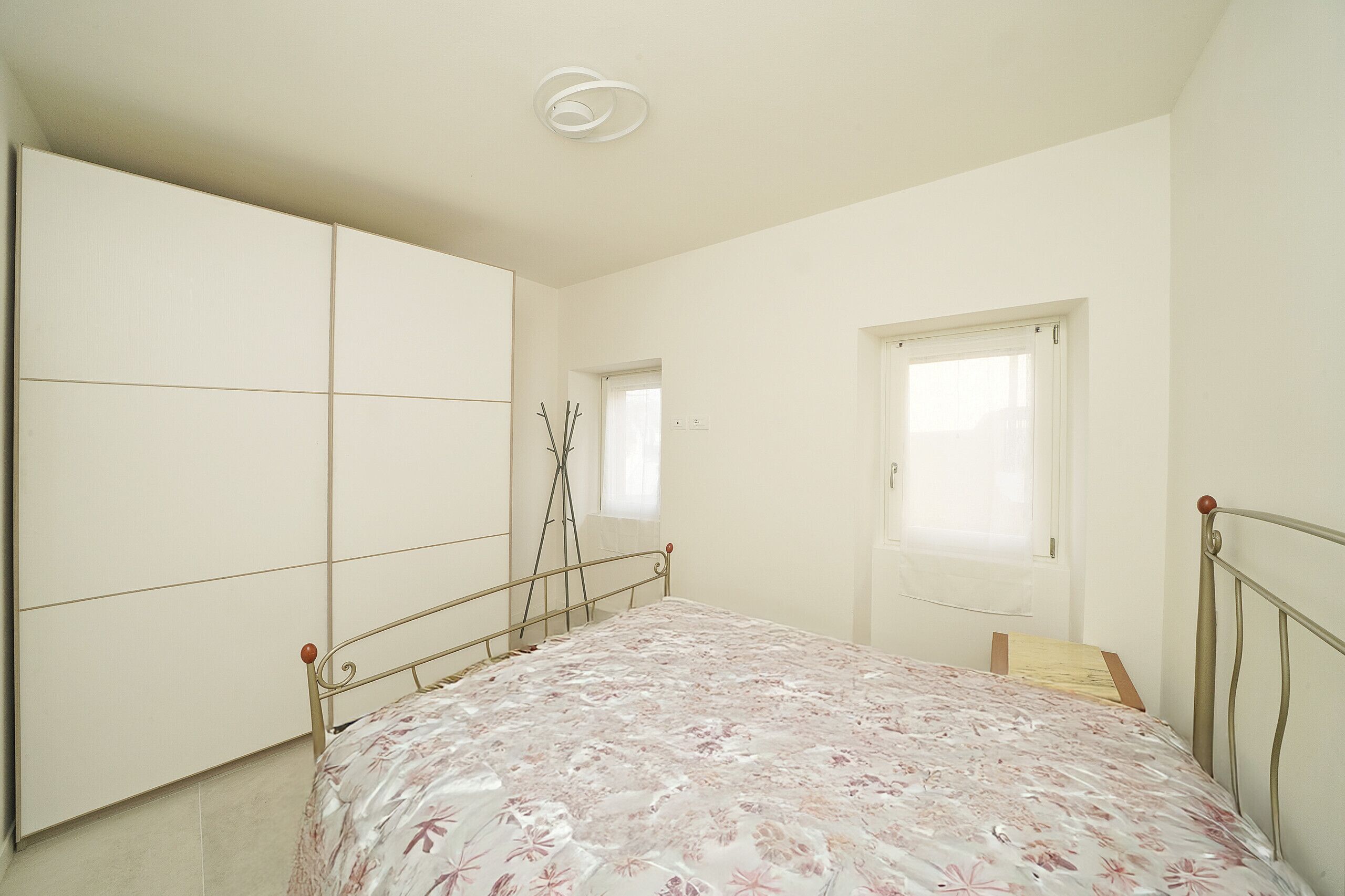A bedroom with a bed, a wardrobe, a window, and a door.