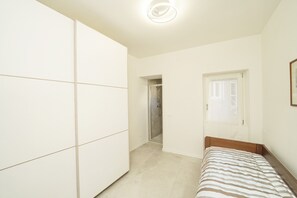 A bedroom with a bed, a wardrobe, and a shower area. - Casa all Angolo Relax (Toscolano Maderno)