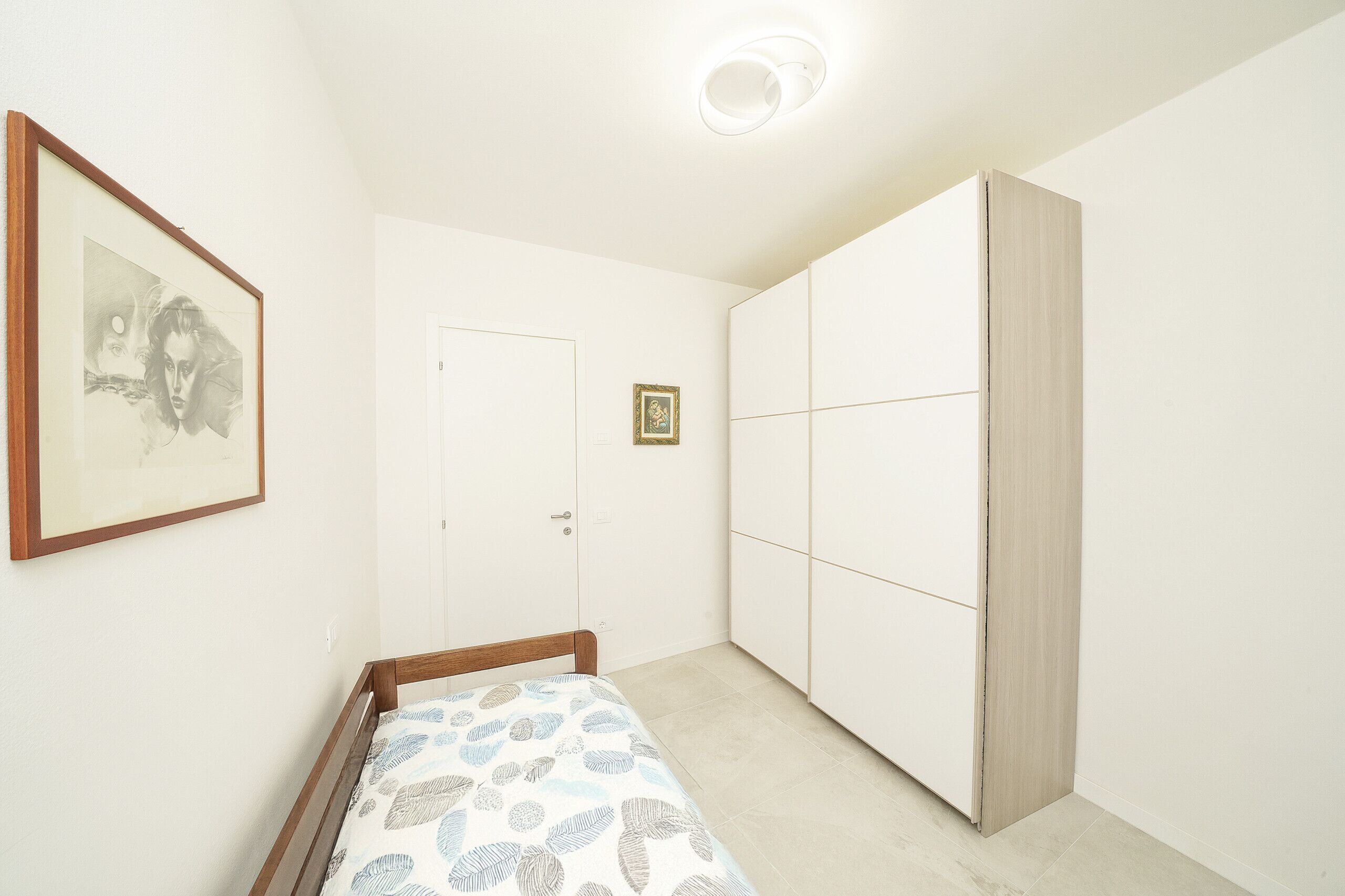 Un dormitorio con cama, armario, puerta y un cuadro en la pared.