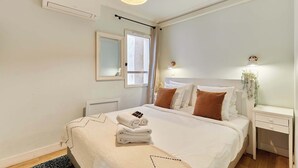 Una camera d'albergo con un letto, un comodino, una lampada e una finestra con tende.