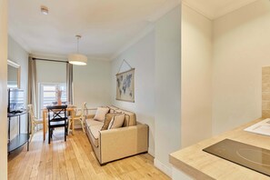 A modern living room with a sofa, dining table, chairs, and a kitchen area with a countertop and stove. - Charming apartment with AC Center of Paris (Paris)