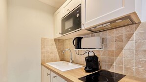 Una cucina dotata di forno a microonde, macchina del caffè e piano cottura a induzione.
