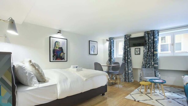 Une chambre à coucher avec un lit, un bureau et une chaise. Il y a des rideaux et une fenêtre.