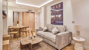 Un soggiorno moderno con un divano grigio, un tavolino rotondo e un'area pranzo con sedie in legno e un tavolo con piano in vetro.