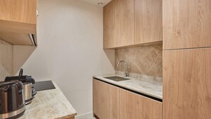 Una cucina compatta con mobili in legno, un piano di lavoro in marmo e un lavello.