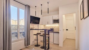 Une cuisine moderne équipée d’un téléviseur à écran plat, de tabourets de bar et d’un petit îlot central.