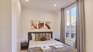 Une chambre à coucher moderne avec un grand lit, un tapis moelleux et des œuvres d’art accrochées au mur.