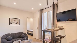 Un salon moderne avec un canapé gris, une petite table basse et un coin repas comprenant une table et des chaises.