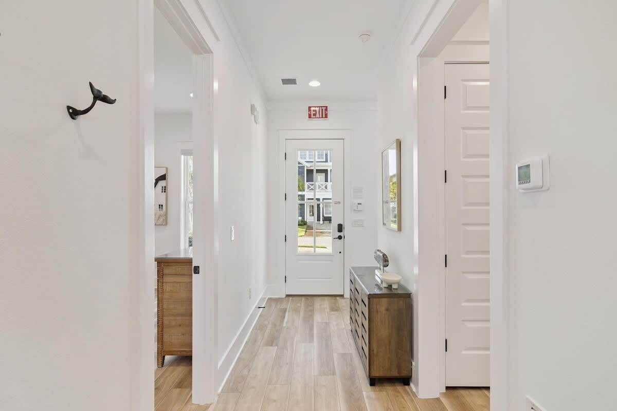 A hallway with a wooden floor, white walls, and a door at the end.