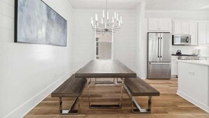 Une cuisine moderne avec des meubles blancs, des appareils en acier inoxydable et une table à manger en bois, accompagnée de bancs.