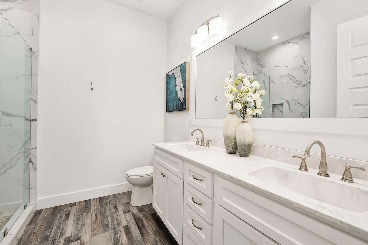 A modern bathroom with a white vanity, a large mirror, and a shower area.