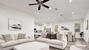 A spacious living room with a large sectional sofa, a coffee table, and a ceiling fan. - Modern 3-story Beach House W Poll and Billiard (Miramar Beach)
