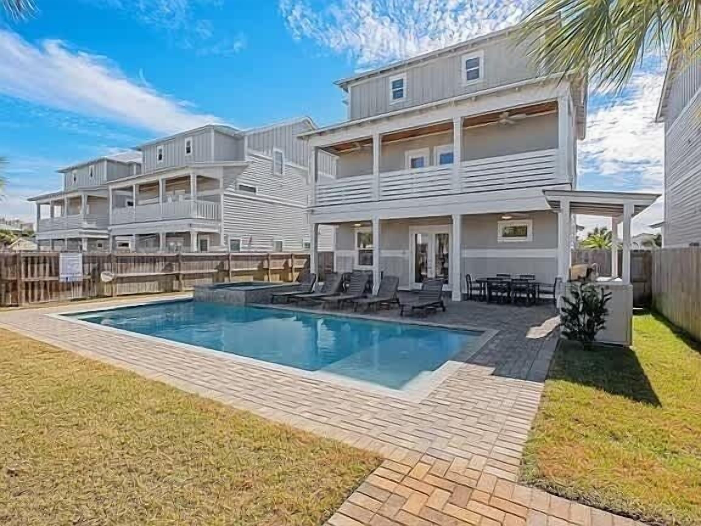A multi-story residential building with a swimming pool, outdoor seating, and a fenced yard.