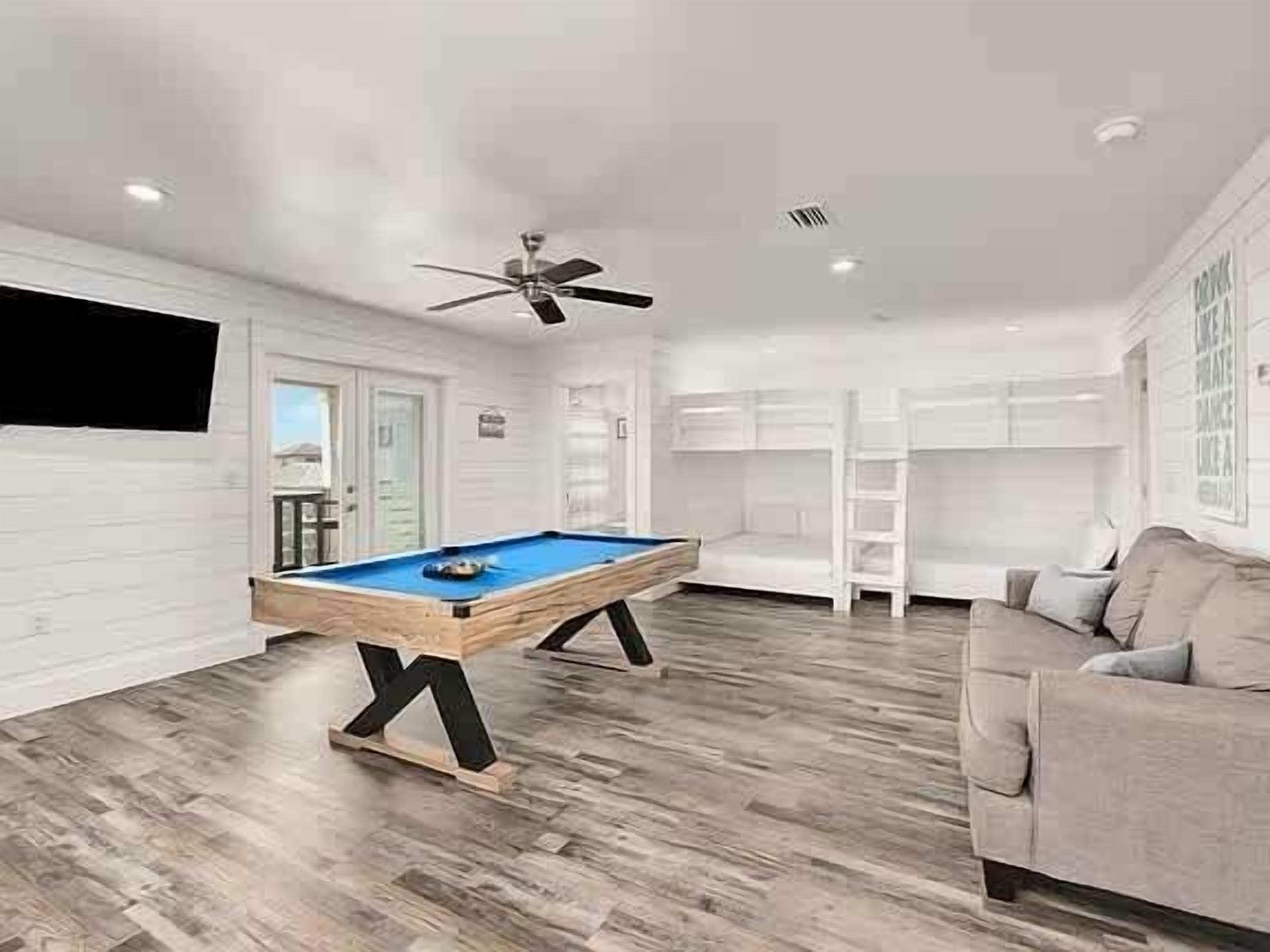 A modern living room with a pool table, a ceiling fan, and a sofa.