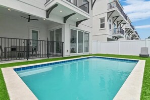 Una casa moderna de dos pisos con piscina, un porche cubierto y fachada blanca.