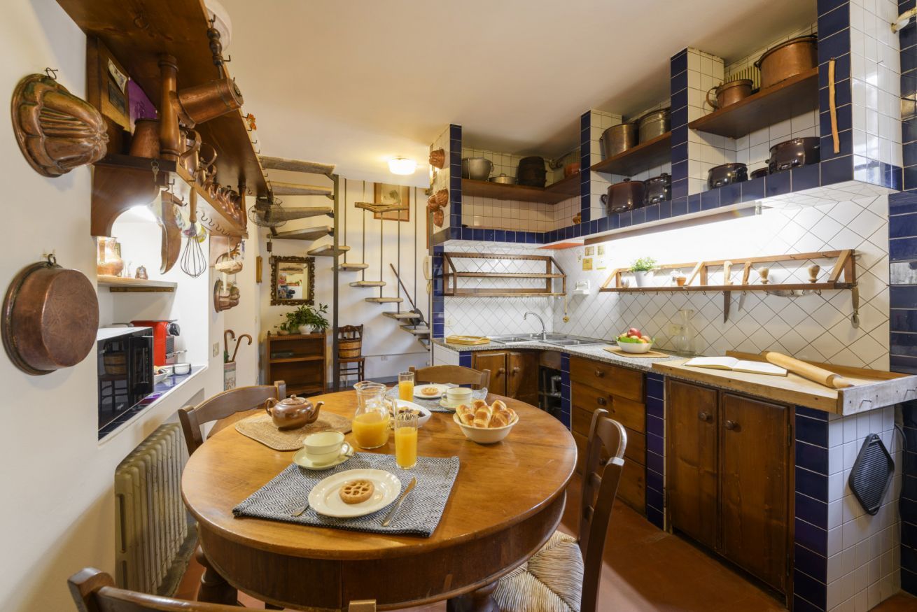 Une cuisine avec des meubles de rangement en bois, une table à manger et divers ustensiles de cuisine.