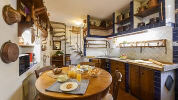 Une cuisine avec des meubles de rangement en bois, une table à manger et divers ustensiles de cuisine.