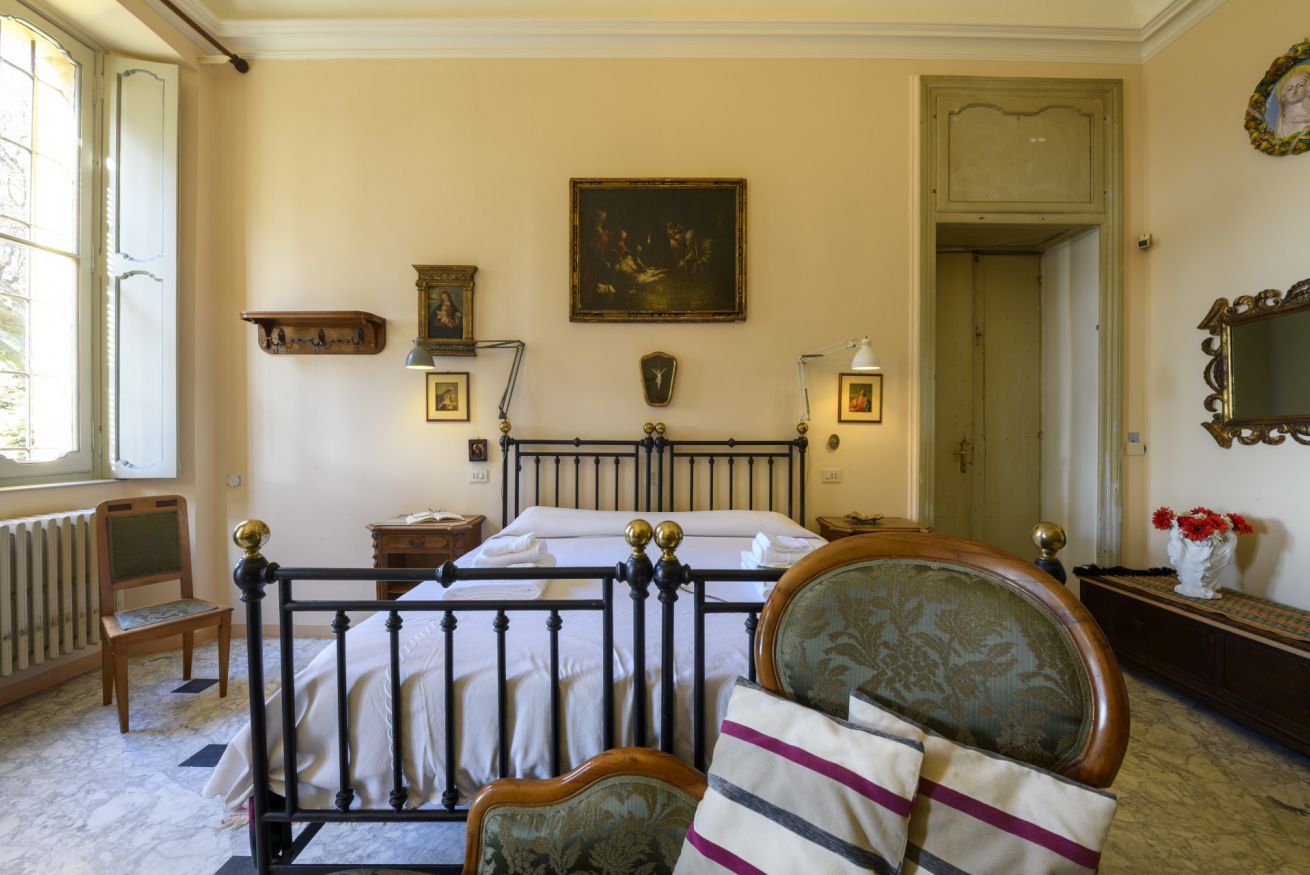 A bedroom with a bed, a chair, a nightstand, a dresser, a mirror, and a door.