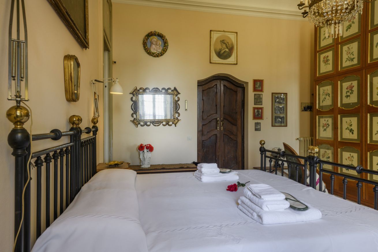 Una habitación de hotel con una cama grande, un armario de madera, un espejo y una araña.
