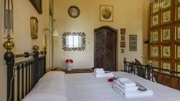 Una habitación de hotel con una cama grande, un armario de madera, un espejo y una araña.