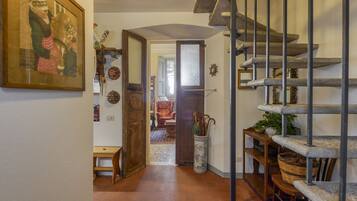 A hallway with a wooden bench, a door leading to another room, a staircase, and a wall-mounted shelf with baskets.